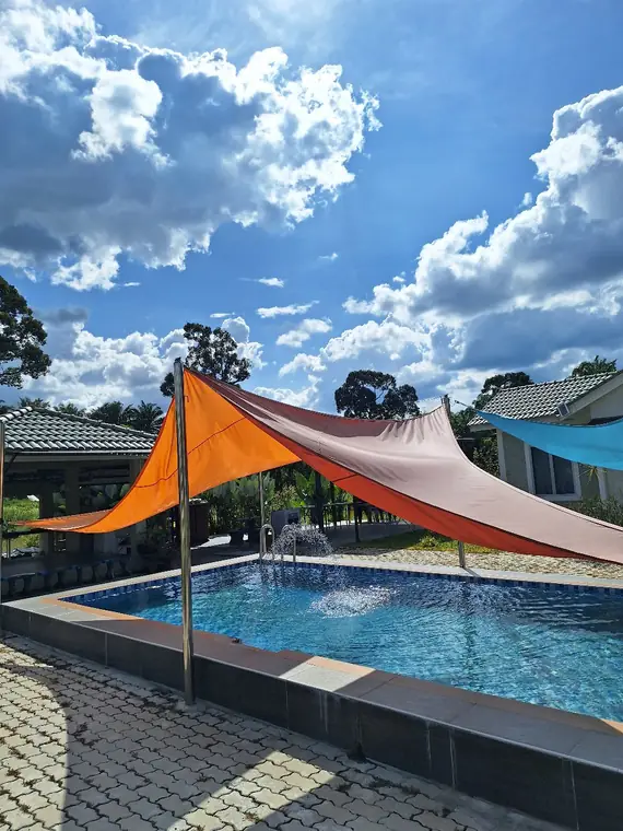 Kolam renang dengan kanopi oren di bawah langit biru